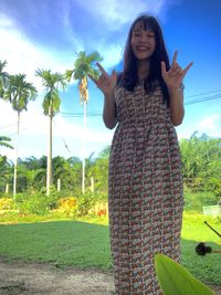 Young woman standing by palm tree on field