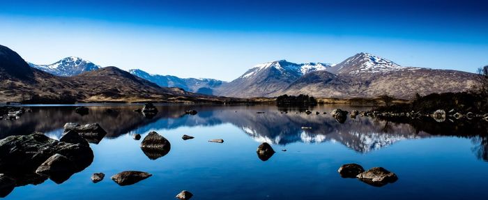 Scenic view of lake and mountains against blue sky