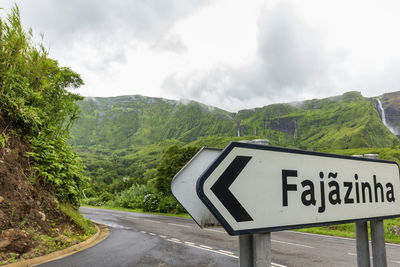 Road sign by mountains against sky