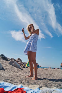 Full length of woman standing at beach against sky