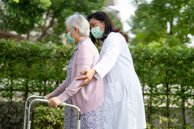 Side view of nurse assisting senior woman at park