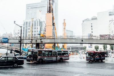 Buses and car moving on wet city street during monsoon