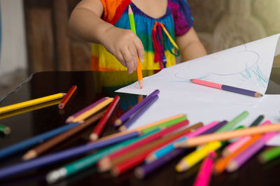 Midsection of woman holding pencils on table