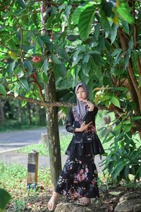 Young woman standing against plants