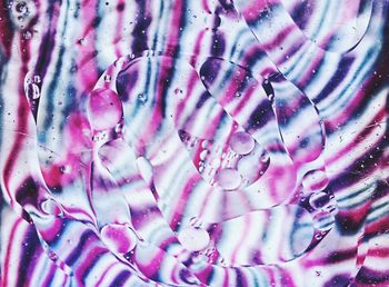 Full frame shot of water on glass against multi colored wall