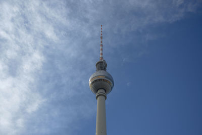 Low angle view of communications tower against cloudy sky