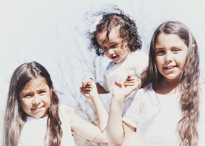 Portrait of sisters holding hands on sunny day