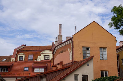 Vintage roofs of houses with windows, balconies and ventilation pipes against sky in old town