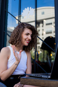 Portrait of young woman sitting in cafe and making video chat