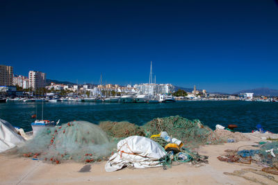 View of cityscape by sea against clear blue sky