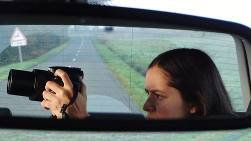 Teenage girl photographing in car