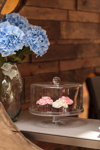 Close-up of cupcakes in cakestand by blue hydrangeas in vase on table