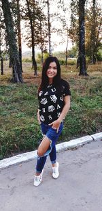 Portrait of smiling young woman standing on field