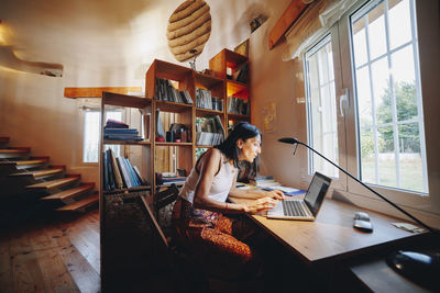 Mature woman using laptop sitting at table in home