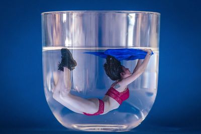 Girl swimming in a glass of water which is actually a composite with upside down model