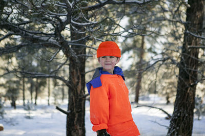 Boy standing on snow covered tree during winter