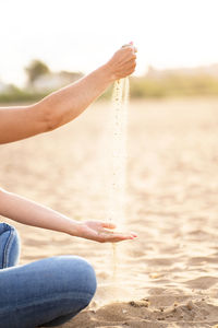 Unrecognizable woman playing with the sand in the beach. horizontal view of summer relax background.