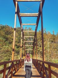 Woman on footbridge against sky