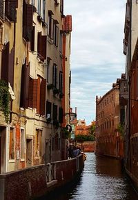 Canal amidst buildings in city against sky