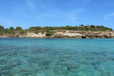 Scenic view of rocks in sea against blue sky