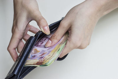 Midsection of person holding cigarette against white background