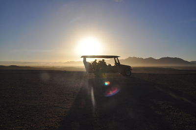 Silhouette people on field against sky during sunset