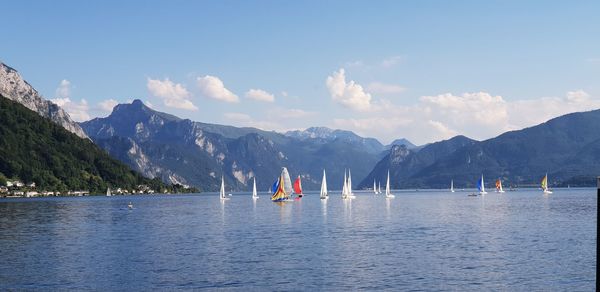 Sailboats in sea against mountains