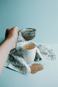 Cropped image of person holding drink on table