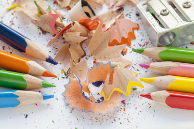 High angle view of multi colored pencils and shavings by sharpener on table