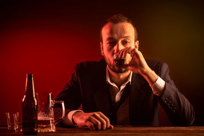 Portrait of a young man drinking glass on table