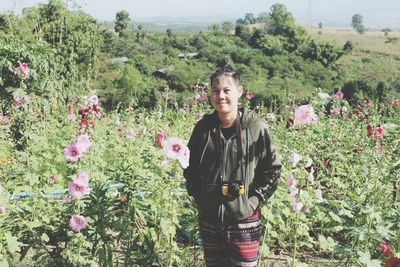 Portrait of young man standing on flowering plants