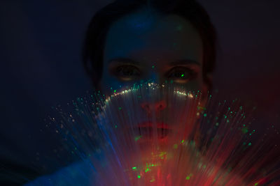 Close-up portrait of young woman against illuminated background