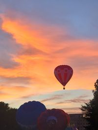 Hot air balloon flying against orange sky