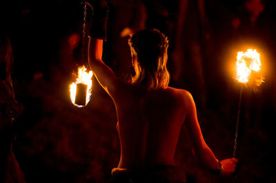 Rear view of topless female fire dancer