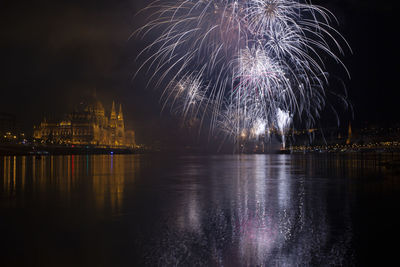 Low angle view of firework display over river at night