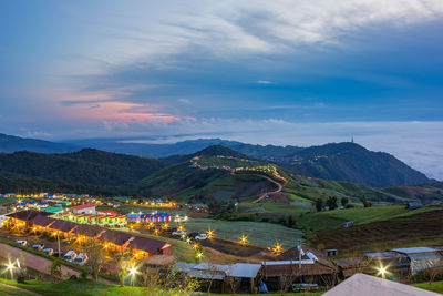 High angle view of illuminated buildings and mountains against sky