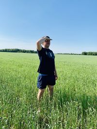 Man shielding eyes while standing on grassy landscape