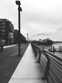 Sidewalk by lake against clear sky