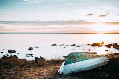 Scenic view of sea against sky during sunset. small boat in foreground. 