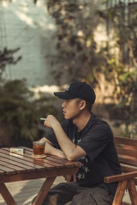 Young man looking away while sitting on table