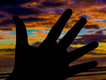 Close-up of silhouette hand against sky during sunset