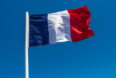 Low angle view of french flag waving against clear blue sky
