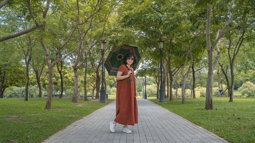 Full length of woman standing against trees