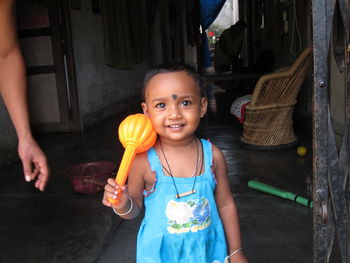 Close-up of person hand by portrait of girl holding toy at home