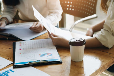 Midsection of woman with coffee cup on table