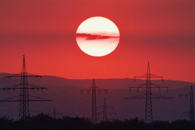 Silhouette electricity pylon against romantic sky at sunset