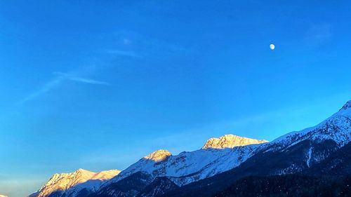 Scenic view of snowcapped mountains against blue sky