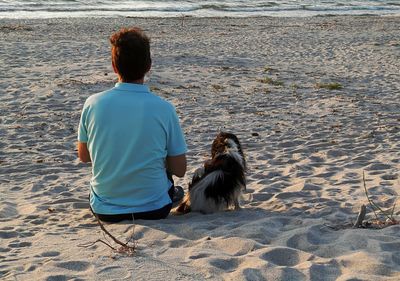 Rear view of man sitting on beach