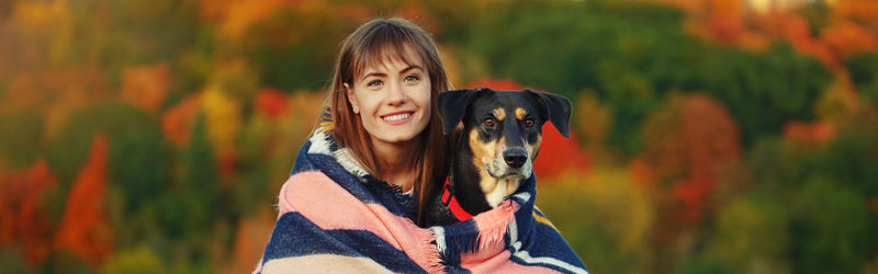Portrait of smiling young woman with dog against blurred background