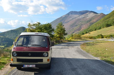 Vintage car on road by mountains against sky